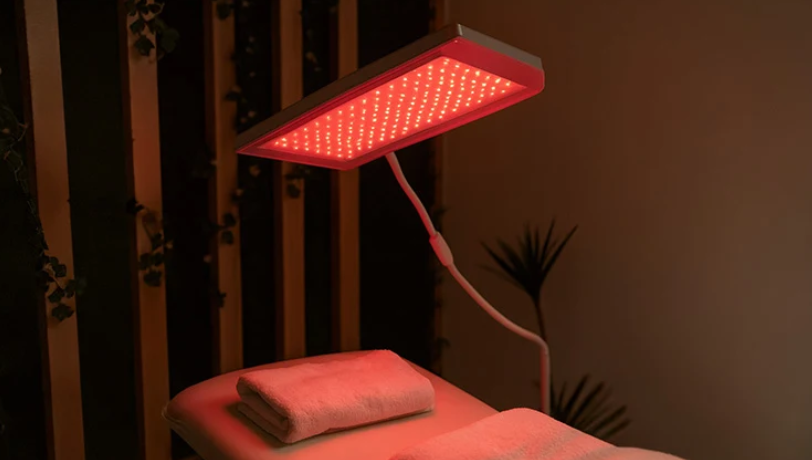 Red light therapy setup over a massage table